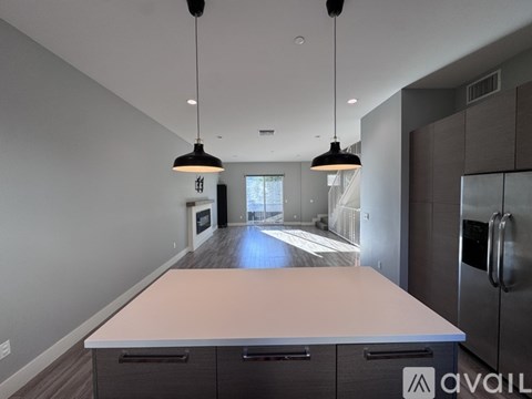 A kitchen with a long counter and a refrigerator on the right side.