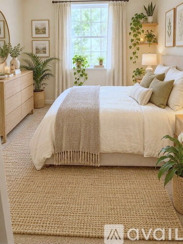 A bedroom with a large bed and a window with curtains.