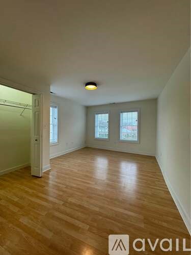 A room with wooden flooring and a window with a view of buildings outside.