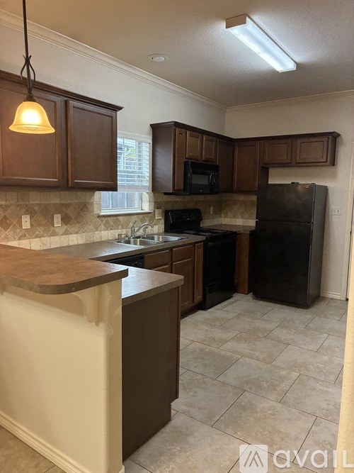A kitchen with brown cabinets and a black refrigerator.