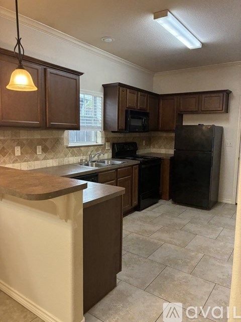 A kitchen with brown cabinets and a black refrigerator.