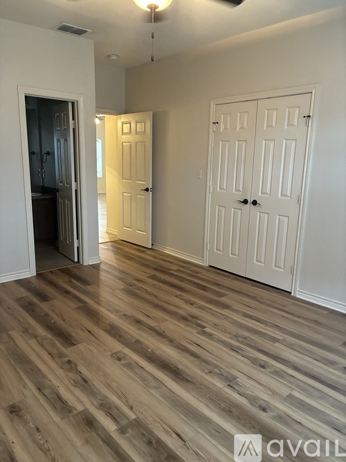 A room with wooden flooring and two white doors.