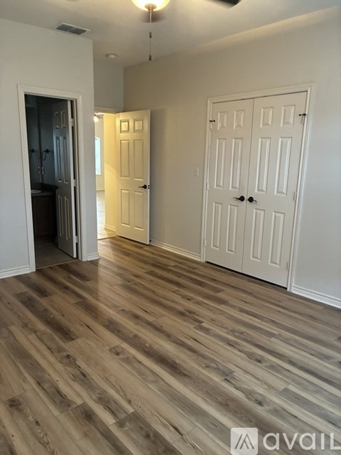 A room with wooden flooring and two white doors.
