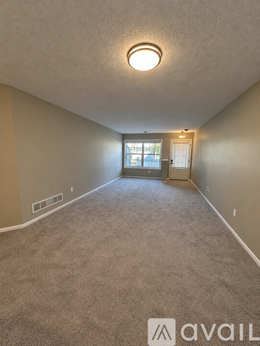 A room with a carpeted floor and a door leading to another room.
