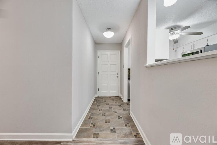 A hallway with a tiled floor and a white door.