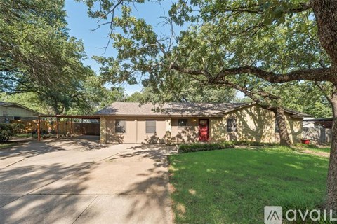 A house with a driveway and trees in front.