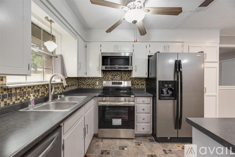 A kitchen with a stainless steel refrigerator and a fan on the ceiling.