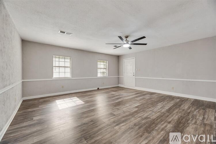 A spacious room with wooden flooring and a ceiling fan.