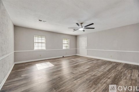A spacious room with wooden flooring and a ceiling fan.