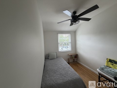 A bedroom with a bed, a window, and a ceiling fan.