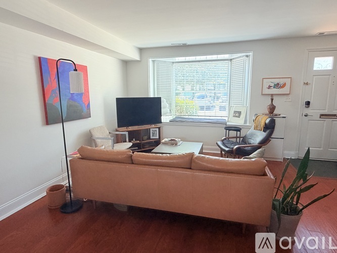 A living room with a brown couch and a painting on the wall.