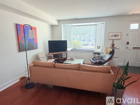 A living room with a brown couch and a painting on the wall.