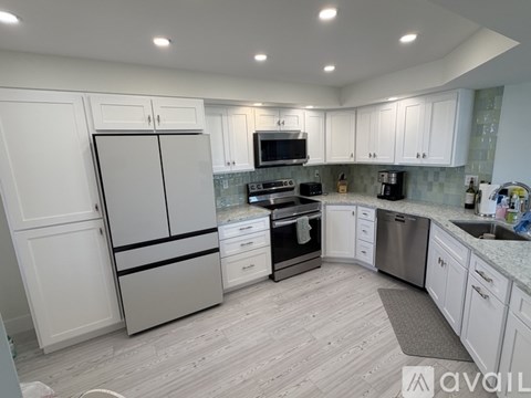 A kitchen with white cabinets and a grey refrigerator.