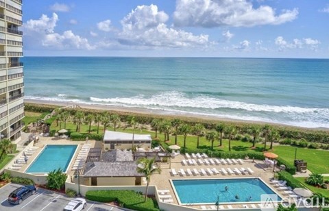 A beachfront hotel with a swimming pool and a view of the ocean.