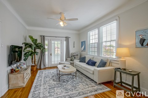 A living room with a white couch, a rug, a ceiling fan, and a painting on the wall.