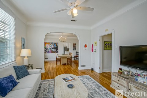 A living room with a white couch, a coffee table, and a ceiling fan.