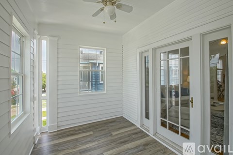 A white room with a ceiling fan and sliding glass doors.