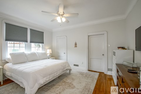 A bedroom with a large bed and a ceiling fan.