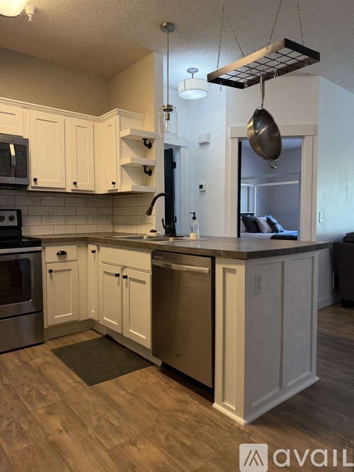 A kitchen with white cabinets and a wooden floor.