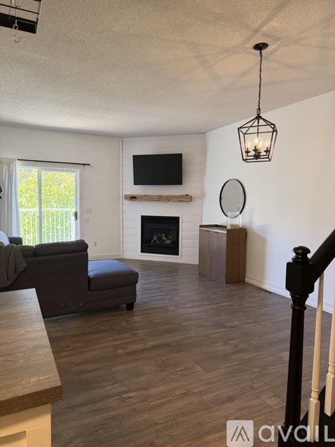 A living room with a fireplace and a grey sofa.