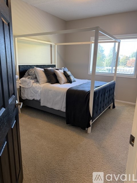 A bedroom with a four-poster bed and carpeted floor.