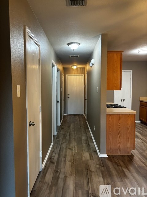 A long hallway with doors on both sides and a kitchen area at the end.