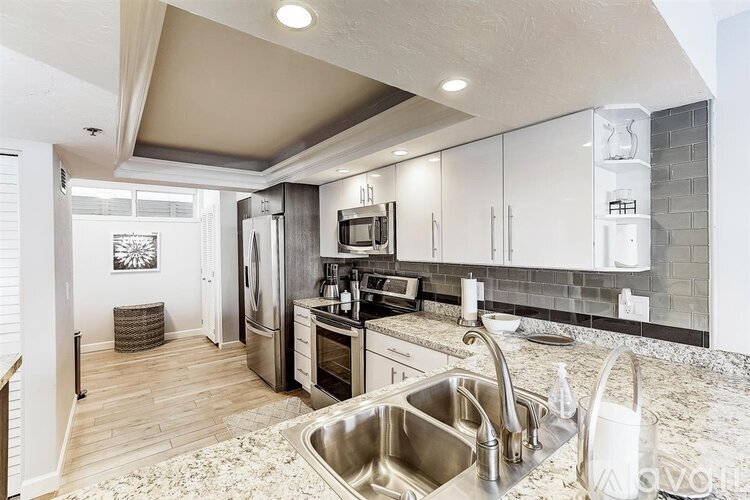 A modern kitchen with a stainless steel sink and white cabinets.