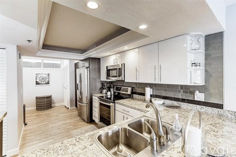 A modern kitchen with a stainless steel sink and white cabinets.