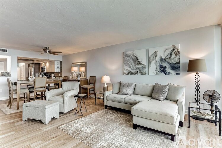 A living room with a white couch, a coffee table, and a rug.