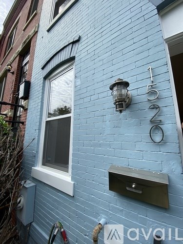 A blue building with a mailbox and a lamp on the wall.