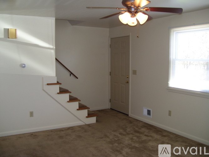 A room with a staircase and a ceiling fan.