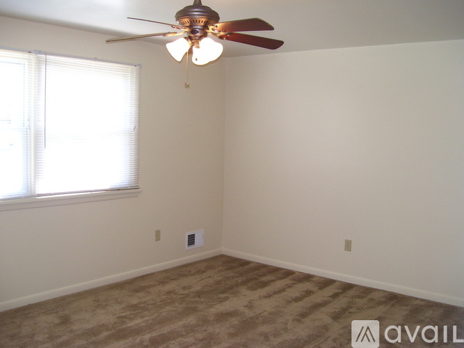 A room with a ceiling fan and a window with blinds.