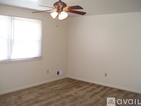 A room with a ceiling fan and a window with blinds.