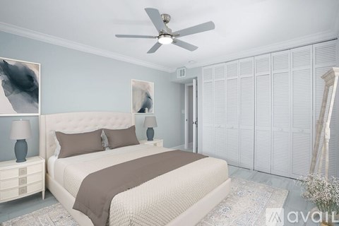 A bedroom with a large bed, a ceiling fan, and two lamps on side tables.