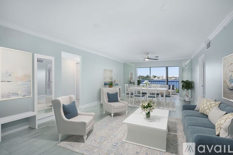A living room with a white sofa, two white chairs, and a coffee table with a vase of flowers on it.