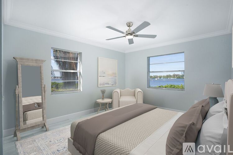 A bedroom with a large bed, a dresser, and a window overlooking the water.