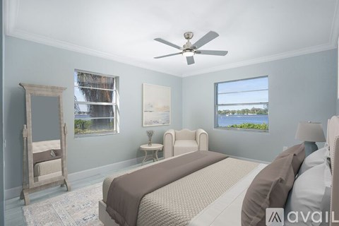 A bedroom with a large bed, a dresser, and a window overlooking the water.