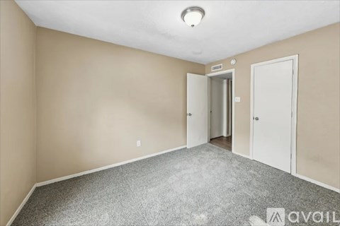 A room with a carpeted floor and two doors.