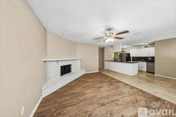 A living room with a fireplace and a kitchen in the background.