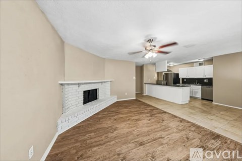 A living room with a fireplace and a kitchen in the background.