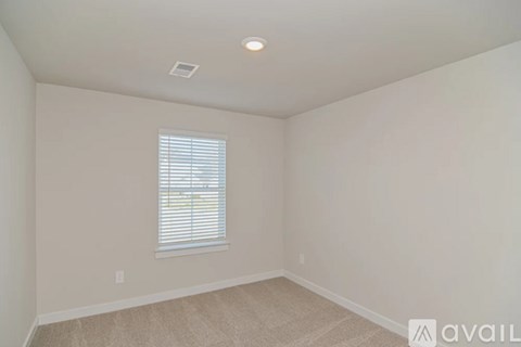 A room with a window and a carpeted floor.