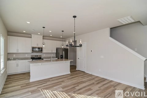 A modern kitchen with white cabinets and a wooden floor.