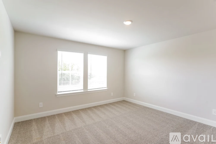 A room with a carpeted floor and two windows.