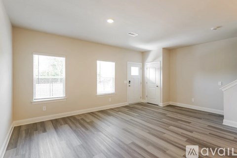 A spacious room with wooden flooring and white walls.