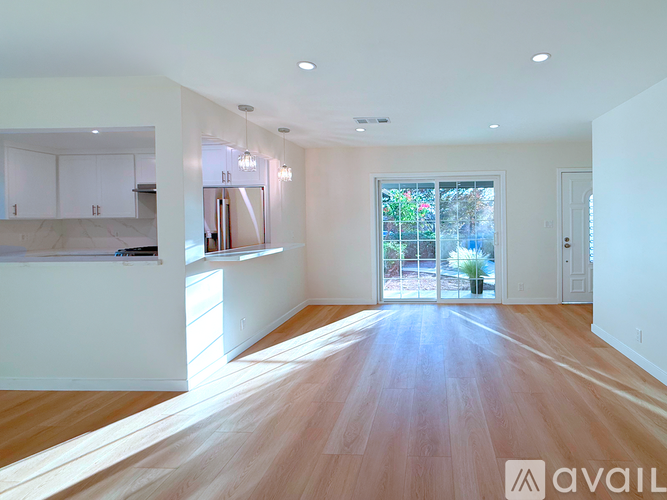 A spacious room with wooden floors and white walls.