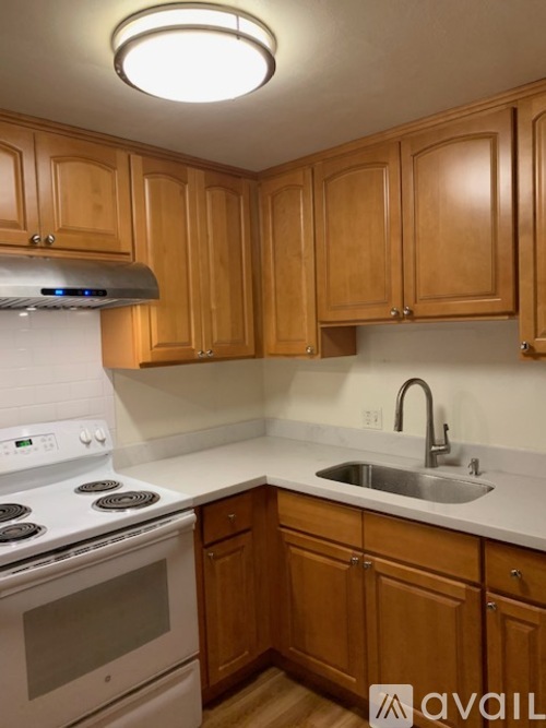 A kitchen with wooden cabinets and a white stove top oven.