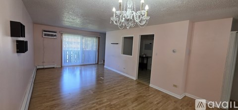 A spacious room with wooden floors and a chandelier.