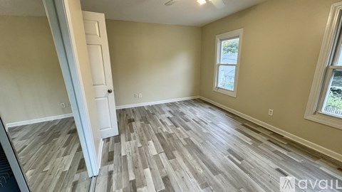 A room with wooden flooring and a window with a view of trees.