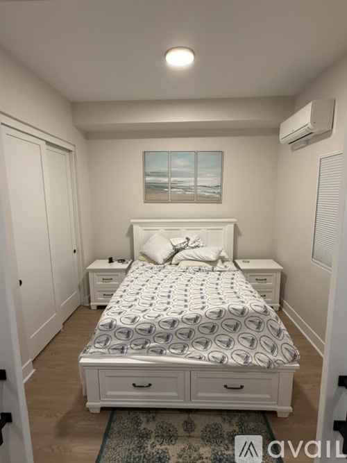 A bedroom with a large bed and a painting on the wall.