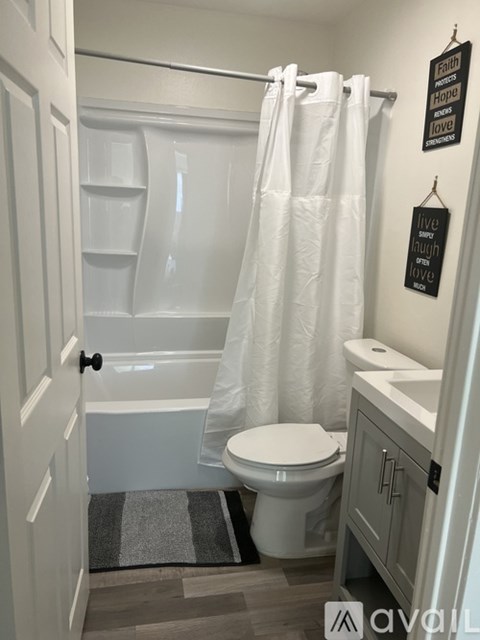 A white bathroom with a toilet, sink, and shower.